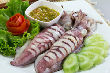 Grilled squid and spicy seafood sauce  with vegetables on white plate, Thai food.