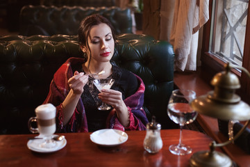 Woman dreaming while eating ice cream in a cafe in the evening.