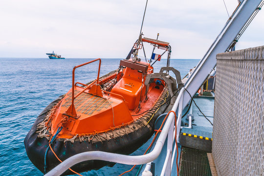 Lifeboat or FRC fast rescue craft boat in the vessel at sea. dsv diving ship is on background.