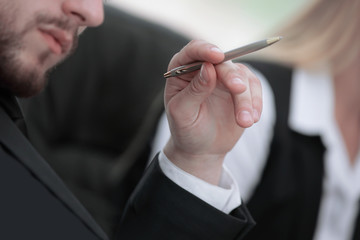 close up. pensive businessman with pen sitting at table