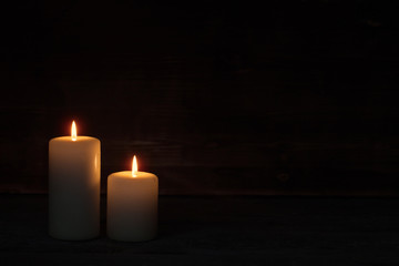 Fototapeta na wymiar Burning candle on old wooden background
