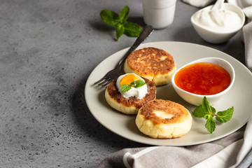 Cottage cheese pancakes or fritters with jam, natural yogurt or sour cream and mint. Traditional Ukrainian and Russian cuisine. Syrniki. Healthy and diet breakfast.