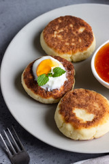 Naklejka na ściany i meble Cottage cheese pancakes or fritters with jam, natural yogurt or sour cream and mint. Traditional Ukrainian and Russian cuisine. Syrniki. Healthy and diet breakfast.