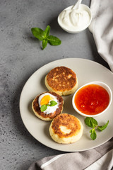 Cottage cheese pancakes or fritters with jam, natural yogurt or sour cream and mint. Traditional Ukrainian and Russian cuisine. Syrniki. Healthy and diet breakfast.