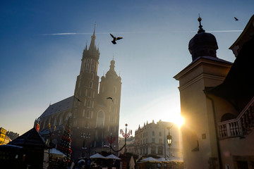View on the central square and famous st. Mary's basilica with pigeons flying during the sunrise in...