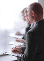 image of a businessman being at the conference and making notes on the foreground