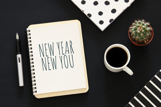 Top view of notebook and text NEW YEAR NEW YOU, cup of coffee over wooden desk.