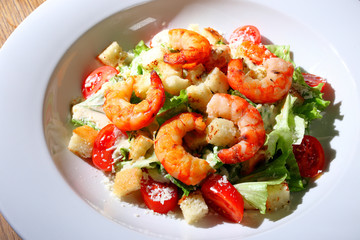 The best fresh salad of prawns in the white dish. Caesar salad with fried shrimps, tomatoes, cheese, lettuce. Healthy food concept. - Stock image
