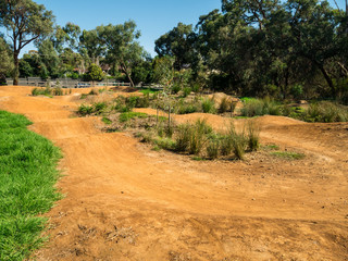 Jumps and obstacles on a BMX bike race track in a suburban park.