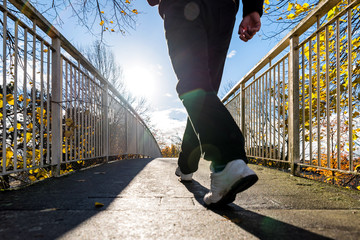 bright sunny morning view of man walking on pedestrian bridge in british autumn