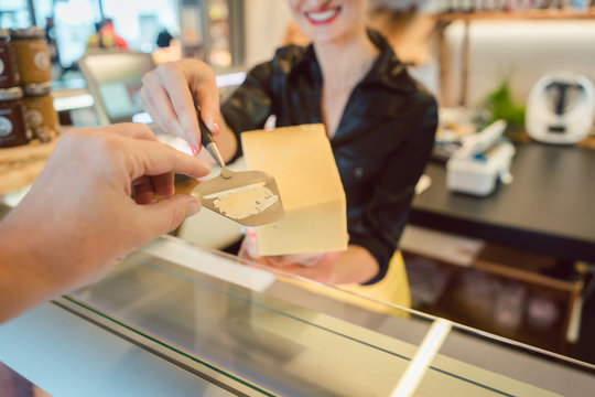 Kunde probiert ein St&uuml;ck K&auml;se an der K&auml;setheke 