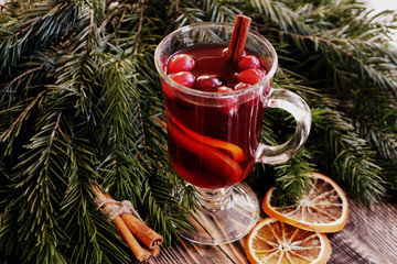 Christmas mulled wine with cranberries in glass Winter warming drink with spices decorated with fir...