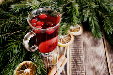 Christmas mulled wine with cranberries in glass Winter warming drink with spices decorated with fir...