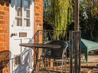 sunny day view of old white door on old brick wall blocked by metal table in england