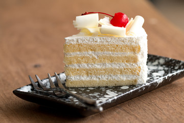 Piece of white cake with vanilla frosting and cherry jelly, topped with white cheese