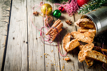 Traditional Christmas pastries, Italian homemade double-baked biscotti or cantuccini cake, with nuts and dried fruits. with xmas decorations and fir branches, old wooden background copy space