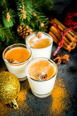 Christmas eggnog liqueur drink or cola de mono cocktail. traditional winter cocktail in short glasses, with xmas decorations, dark background copy space