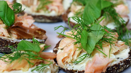Delicious smoked salmon canapes. Rye bread with fish, cream cheese, dill and basilica toppings. 