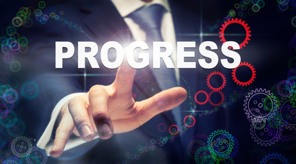 A businessman pressing a Progress business concept on a graphical display of cogs