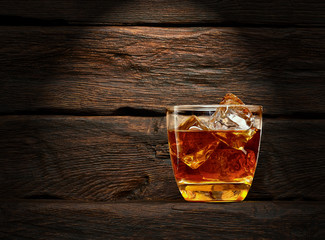 Bottle and glass of whiskey on wooden table or desk background