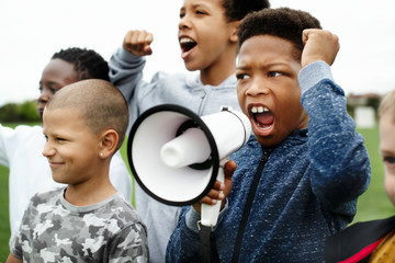 Young boy shouting on a megaphone in a protest - obrazy, fototapety, plakaty