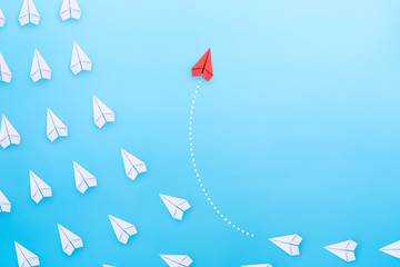 Group of white paper plane in one direction and one red paper plane pointing in different way on blue background. Business concept for new ideas, creativity, innovation and solution.