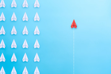 Group of white paper plane in one direction and one red paper plane pointing in different way on blue background. Business concept for new ideas, creativity, innovation and solution. - obrazy, fototapety, plakaty