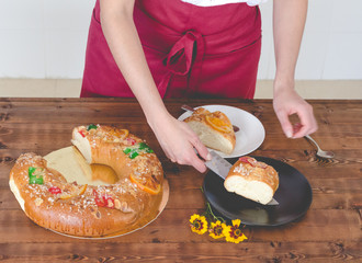 Waitress with uniform cutting and serving cake of kings day.