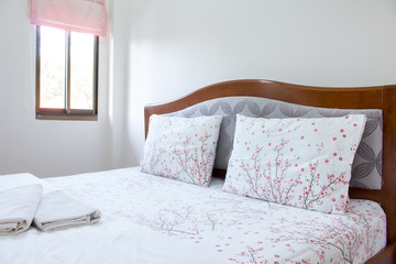 Close up white pillow and bedding sheets on natural white wall bedroom background, Messy bed concept