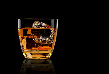 Whisky or whisky in glass on reflective black background