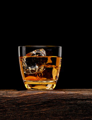 Whisky or whisky in glass on wooden table with black background