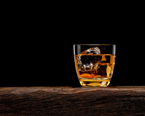 Whisky or whisky in glass on wooden table with black background