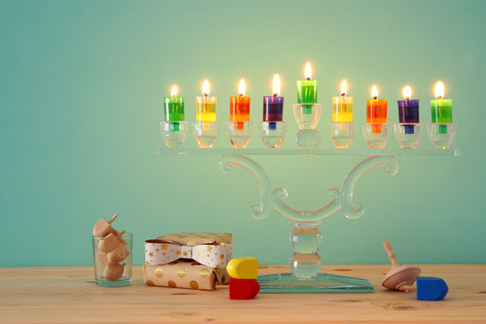 image of jewish holiday Hanukkah background with crystal menorah (traditional candelabra) and colorful oil candles.