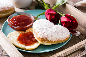 Valentine's Day breakfast with coffee, heart-shaped bun, berry jam and roses on a tray. Close up