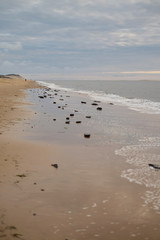 Landscape on a deserted empty Dune du Pilat. looking along the shore with foam waves on sand vast sea calm with grey skies and coastline with tide coming in late Summer