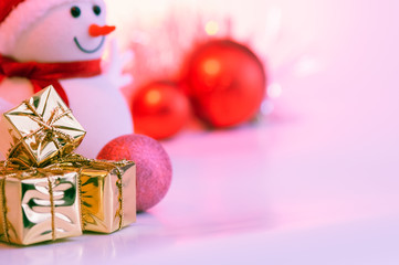 Merry Christmas, New Year, snowman, gifts in gold boxes and red balls on a pink background.