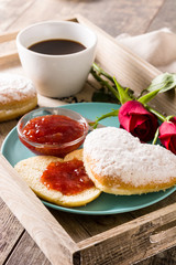 Valentine's Day breakfast with coffee, heart-shaped bun, berry jam and roses on a tray
