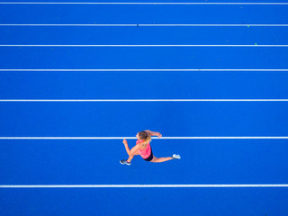 Overhead view of female runner running on tartan track