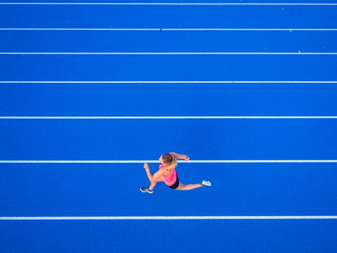 Overhead view of female runner running on tartan track