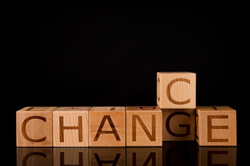 Wooden cube flip with word "change" to "chance" on black reflecting table, development and career growth and change concept