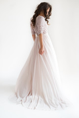 Fototapeta premium morning of the bride. the bride is standing back, beautiful curls, a gentle wedding dress studio, white background