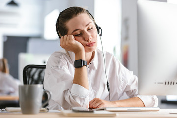Bored young woman wearing microphone headset