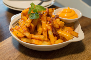 Homemade salty cheese French fries with bacon. Fast food.