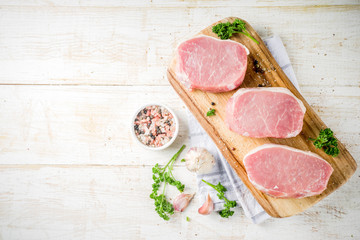 Cooking meat dinner background. Raw fresh meat, pork brisket boneless steak, with spices, herbs, olive oil, top view