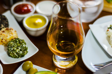 glass of whisky single malt and set with different appetizers in small portions