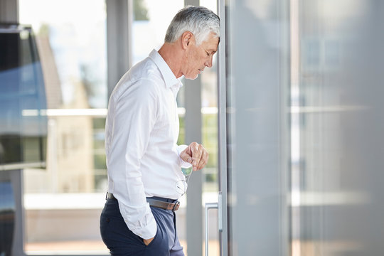 Side view of businessman touching head on windowpane