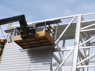 Naklejka premium Construction worker at construction site using lifting boom machinery