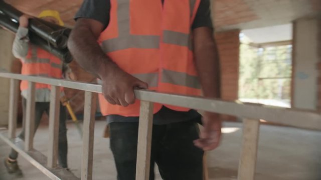 People working in construction site. Men at work in new house inside apartment building. Team of professional manual workers using tools and equipment for profession and job