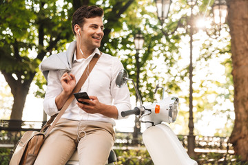 Happy young businessman sitting on a motorbike outdoors