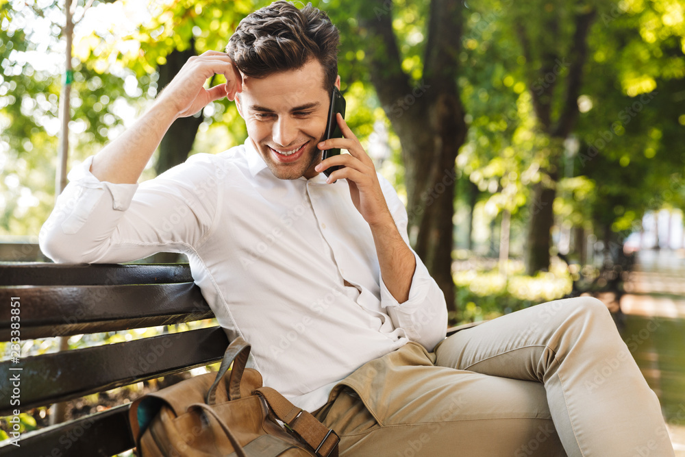 Sticker Happy young businessman sitting on a bench outdoors